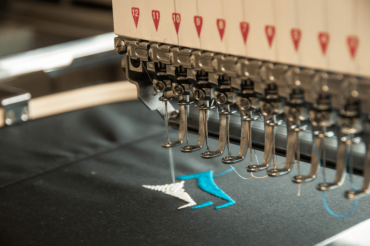 Embroidery machine stitching a blue and white design on fabric.